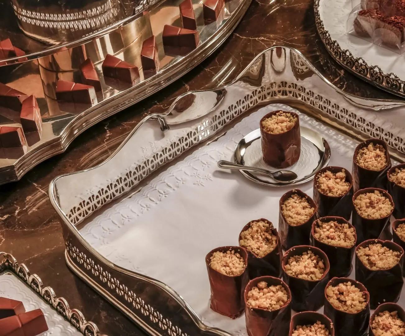A mesa de bolo e doces é um ponto importante da festa de bodas de prata. Capriche na organização. Bandejas prata e toalhas de papel da Relevo são uma boa ideia para valorizar a decoração.