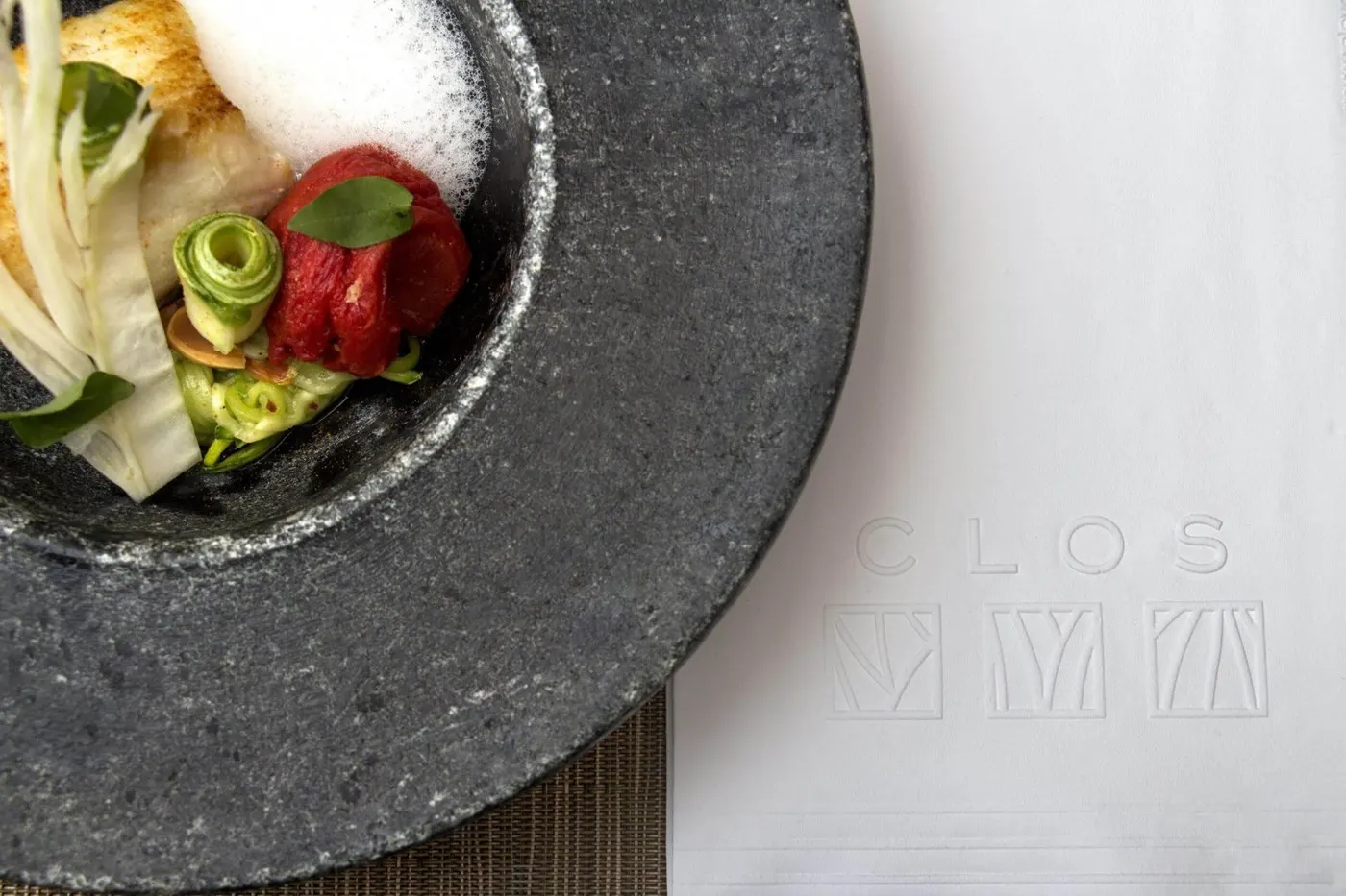 A utilização de louças diferentes ou coloridas também pode ser interessante. Neste exemplo, o prato rústico já é um item decorativo. O guardanapo de papel personalizado com a marca do restaurante dá o complemento que a mesa precisa sem a necessidade de outros itens decorativos para deixá-la bonita e convidativa.